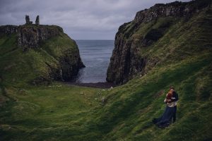 adventurous couple embracing near the ruins of a castle in northern ireland
