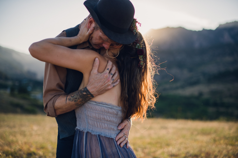 bohemian couple embraces at sunset in the colorado mountains