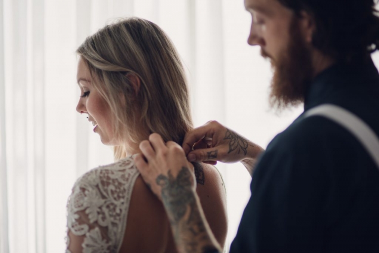 groom fastening brides dress before elopement