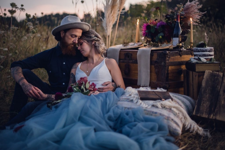 bohemian newlywed couple sitting in a field after elopement