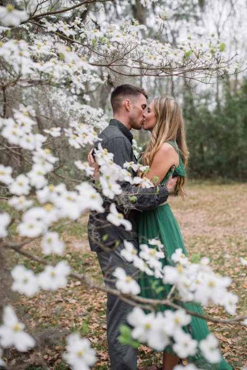 green dress couple kiss by dogwood tree