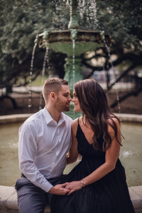 engaged couple face to face in front of fountain