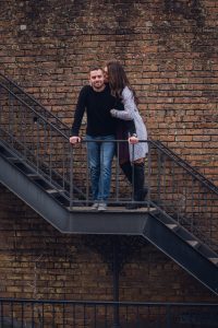 engagement couple in front of brick wall on stairs