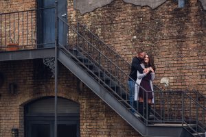 engagement couple embracing in front of brick wall on stairs