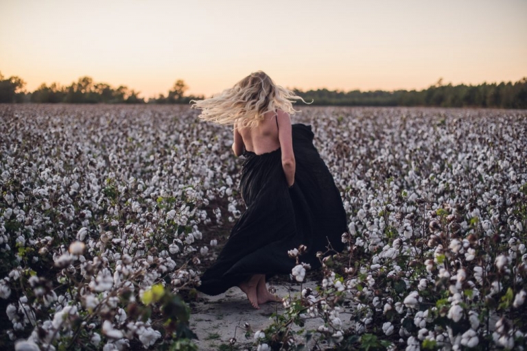 woman twirling in black dress in a cotton field