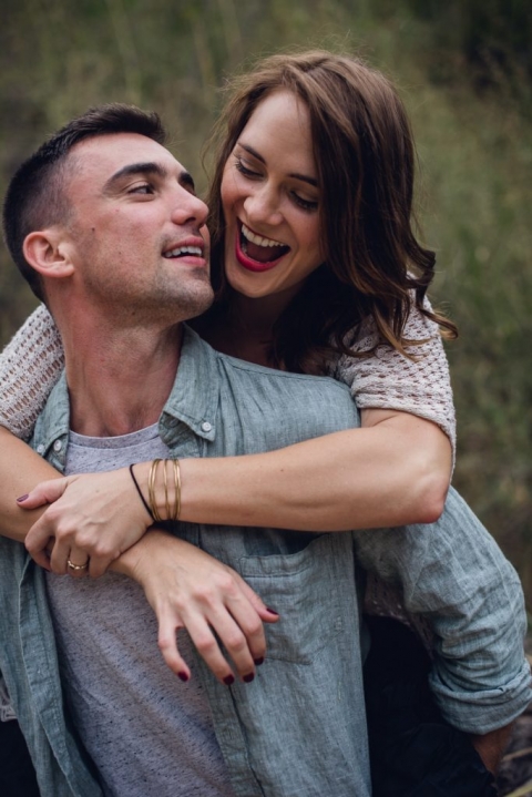 adventurous couple laughing during piggy back ride