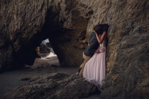 adventurous couple intimately embracing against rocks