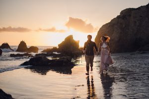adventurous couple running along the beach at sunset