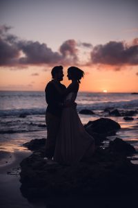 adventurous couple embracing at sunset on the beach