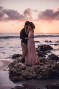 adventurous couple embracing at sunset on the beach