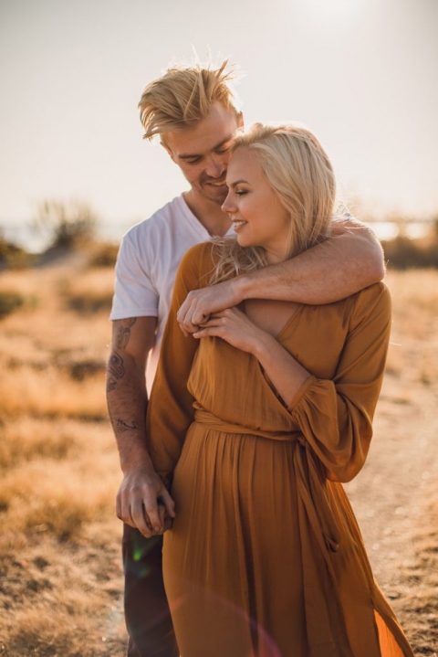 adventurous couple embracing in golden grass