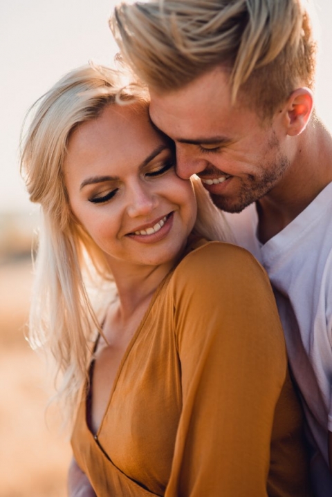 adventurous couple embracing in golden grass