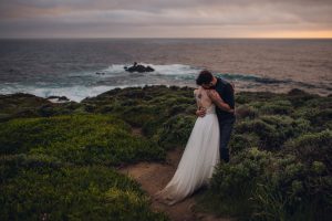 adventurous couple embracing on big sur cliff during their elopement wedding