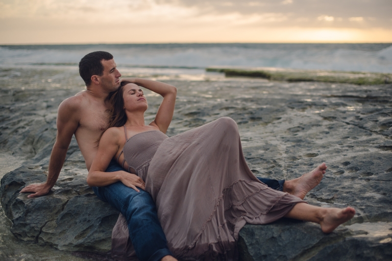 honeymoon couple laying on a rock in the ocean in hawaii