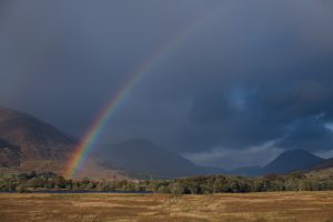 rainbow in front of dark clouds in the scottish highlands