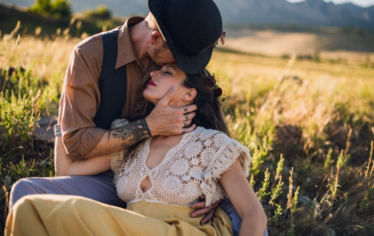 man kissing a woman in a yellow dress surrounded by golden grass in boulder