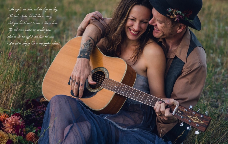 bohemian couple snuggling while holding a guitar