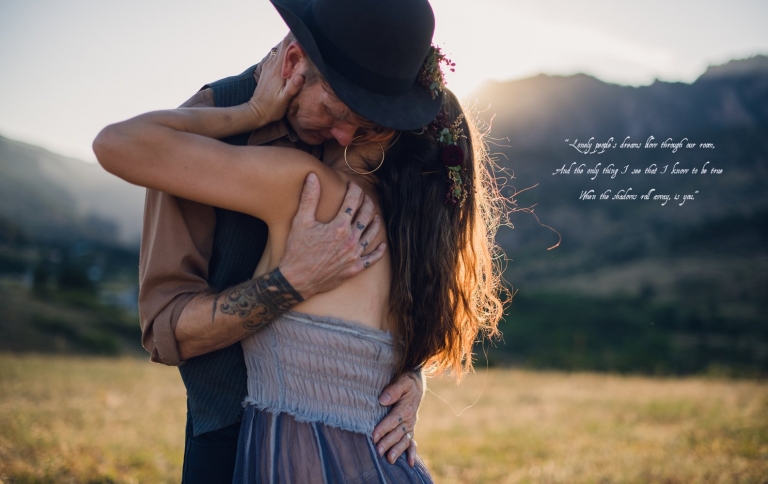 couple embraces at sunset in front of boulder mountains