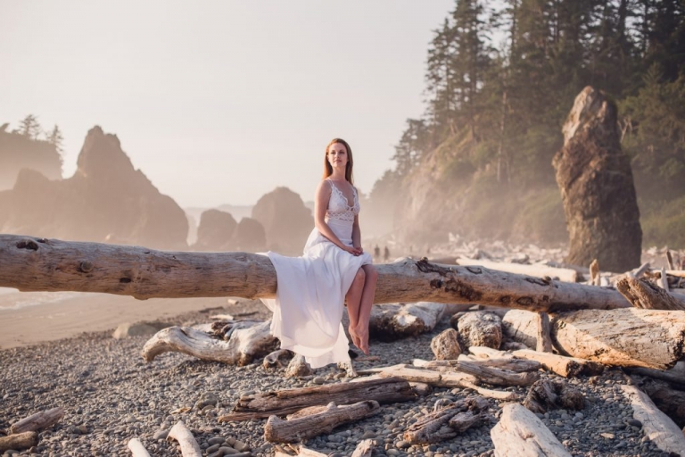 bride sitting on a rocky driftwood beach at sunset in olympic national park