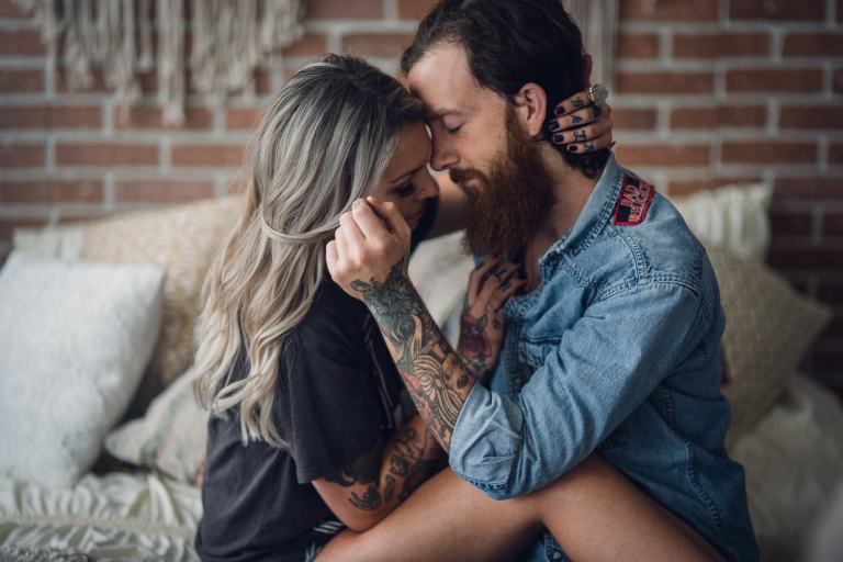 couple sharing an intimate embrace in the bedroom of their seattle loft during their anniversary photo session