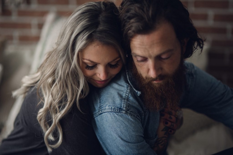 blonde woman presses her face close to her fiance while hugging him during their seattle engagement session at home