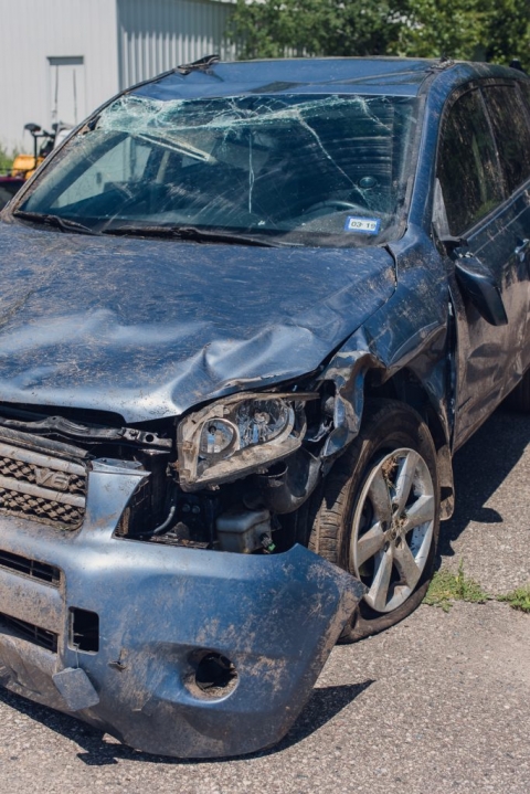 smashed windshield and hanging bumper on a blue toyota rav4 after it collided with a deer, flipped into the air and landed upside down